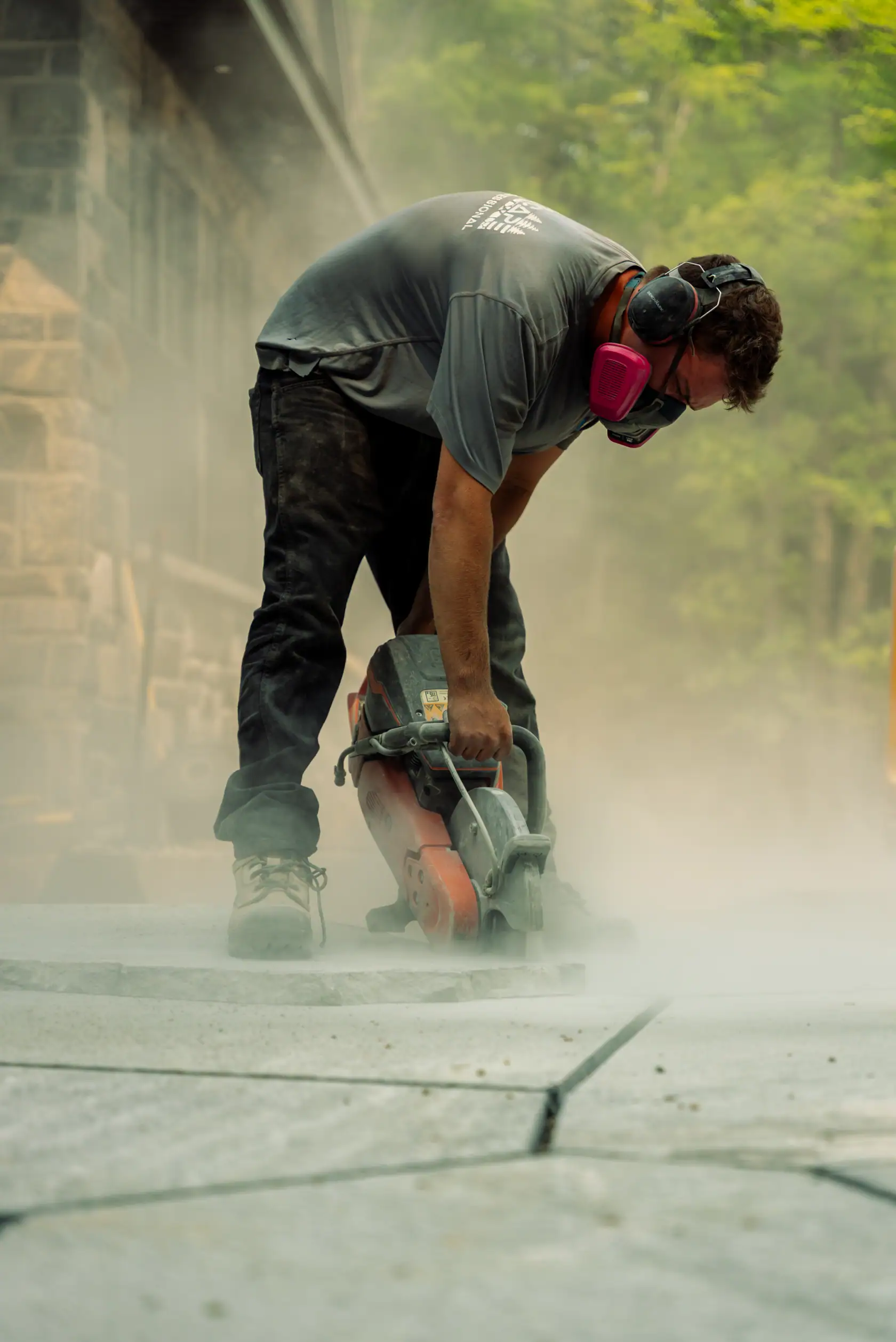 Stonemason cutting flagstone in a cloud of dust